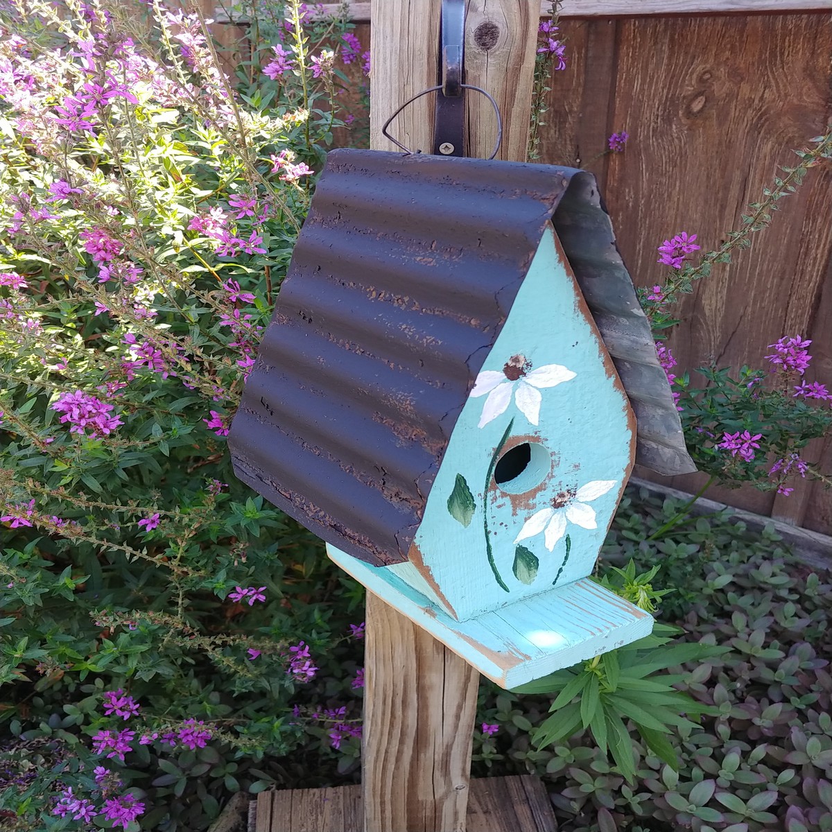 A Framed Bird House With Hand-Painted Flowers And Metal Roof